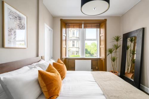- une chambre avec un lit doté de draps blancs et une fenêtre dans l'établissement The Holyrood Park Apartment, à Édimbourg