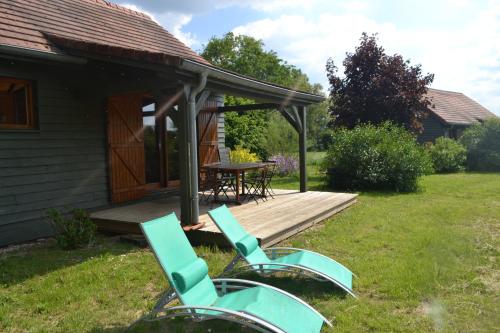 two chairs and a table on a wooden deck at Chalet au bord d'un étang, près d'une ferme pédagogique in Château-Voué