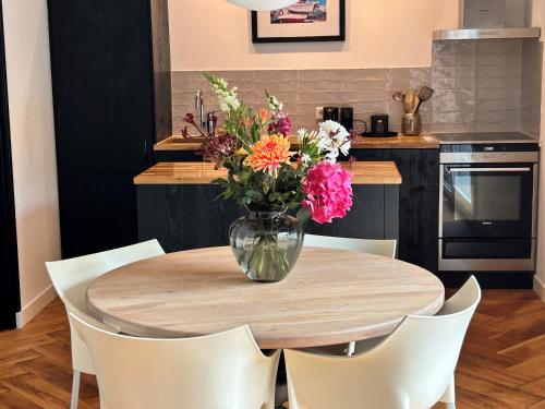 a vase of flowers on a wooden table in a kitchen at Casa Clementine - Boutique Guesthouse in Veldhoven