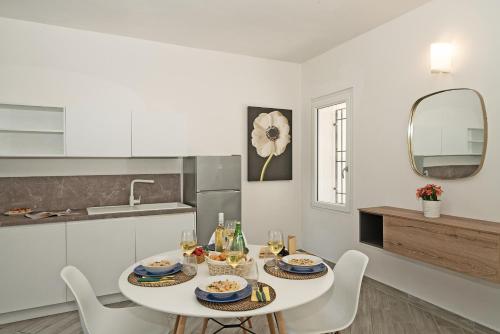 una cucina bianca con tavolo e sedie bianchi di San Carlo Borromeo Apartments by Wonderful Italy a Soiano del Lago
