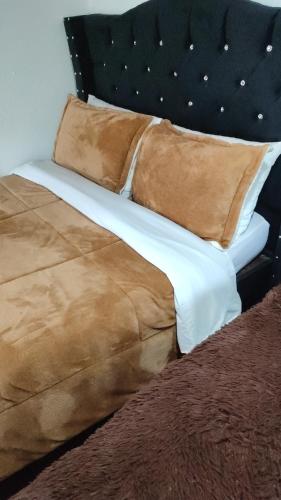 a bed with a brown blanket and pillows on it at Cabañas Casa Campo Guatavita in Guatavita