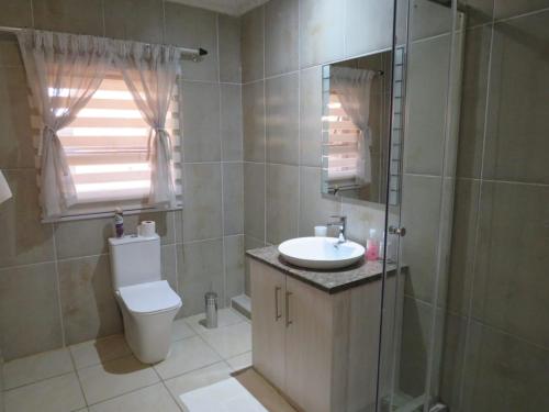 a bathroom with a toilet and a sink and a shower at Kgatholoha Guest House in Klerksdorp