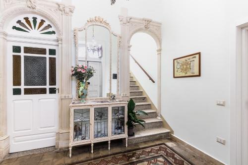 einen Flur mit einer weißen Tür und einer Treppe mit einem Spiegel in der Unterkunft Liberty Suite Regina Elena in Avola