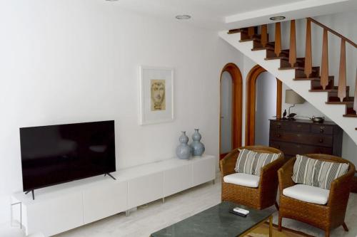 a living room with a flat screen tv and two chairs at Lisbon Surf + Beach Villa in Costa da Caparica