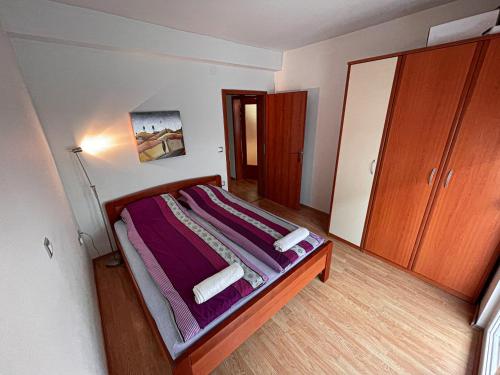 a bedroom with a bed with purple sheets and a cabinet at Korun's Lakeview Apartment in Lagadin