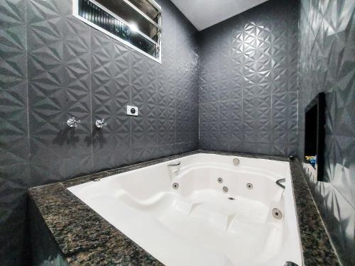 a white bath tub in a bathroom with gray walls at Calamares Hotel São Caetano in São Caetano do Sul