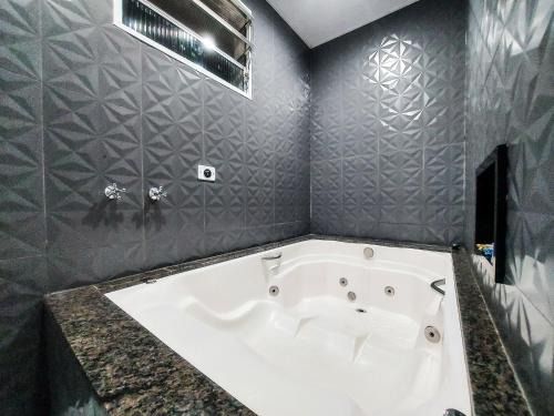 サン・カエタノ・ド・スルにあるCalamares Hotel São Caetanoの白いバスタブ付きのバスルーム(灰色の壁)