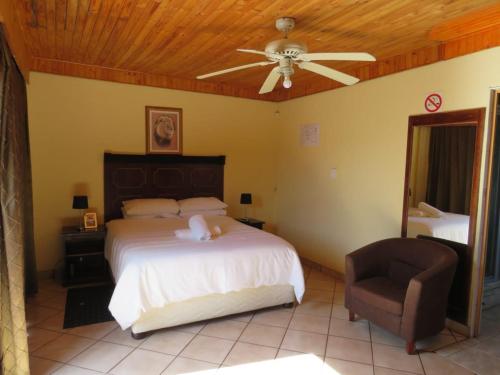 a bedroom with a bed and a ceiling fan and a chair at Kgatholoha Guest House in Klerksdorp