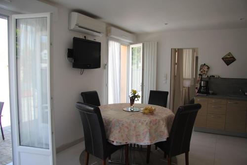 a dining room with a table with chairs and a television at Logement agréable et tranquille in Fontenay-Trésigny