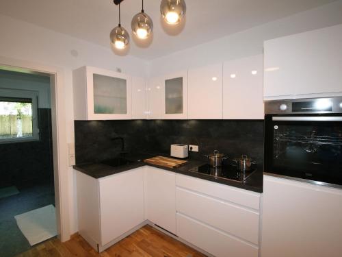 uma cozinha com armários brancos e um balcão preto em Apartment Diwani home stay Innsbruck by Interhome em Innsbruck