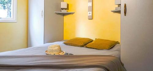 a child wearing a straw hat sitting on a bed at Camping Kévano Plage in Pianottoli-Caldarello