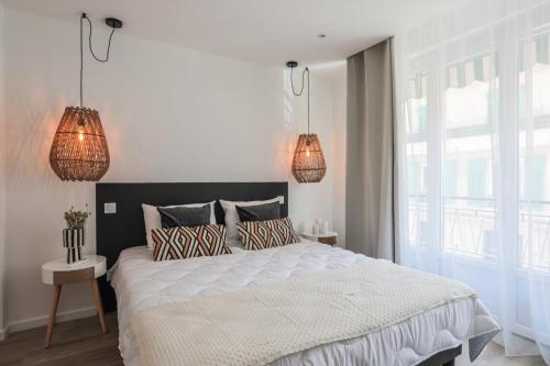une chambre avec un grand lit et deux lampes dans l'établissement Appartement Ebène - Welkey, à Antibes