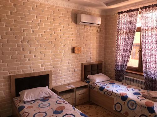 a bedroom with two beds and a brick wall at Sitora Star guest house in Samarkand