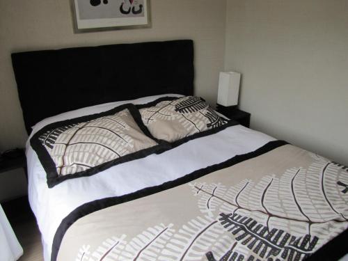 a bed with a black and white comforter and pillows at Apart Hotel Gran Pacifico in La Serena