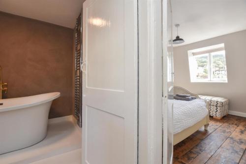 a bathroom with a tub and a bed with a window at Hastings Old town Cottage style in Hastings