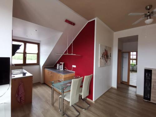een keuken met een tafel en een rode muur bij Studio und Apartment auf dem Pferdehof in Burgpreppach
