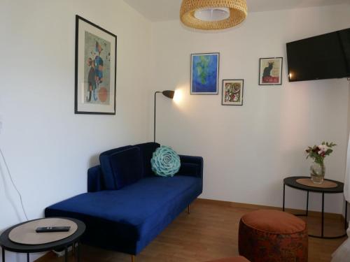 uma sala de estar com um sofá azul e duas mesas em Apartment Casa Lara by Interhome em Olivone