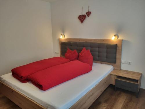 a bed with a red bedspread and two red pillows at Apartment Bergblick by Interhome in See