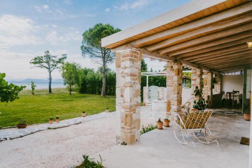 a stone building with a chair on a patio at House by the Sea in Lefkímmi