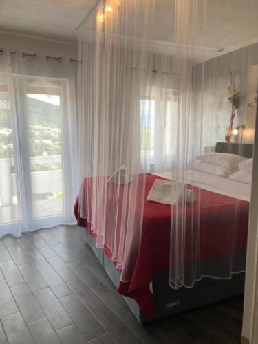 a bedroom with a red and white bed with a window at Apartments Nora & Lucija in Baška