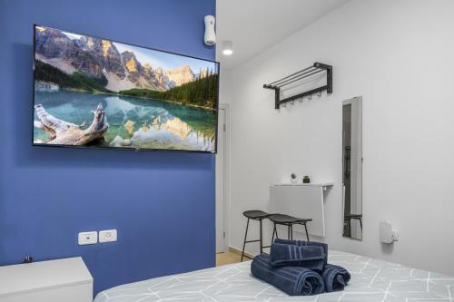 - une chambre avec une télévision suspendue au mur dans l'établissement IB Properties Suites, à Jérusalem