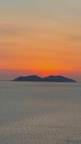 a sunset over the ocean with mountains in the distance at Hotel Kappa3 Villas in Vlorë