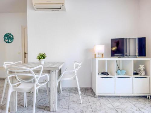une table à manger blanche avec des chaises blanches et une télévision dans l'établissement Apartment Bahia 58 by Interhome, à Empuriabrava