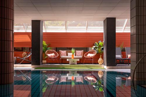 a pool with chairs and a table in a building at Hôtel Diana Restaurant & Spa by HappyCulture in Molsheim