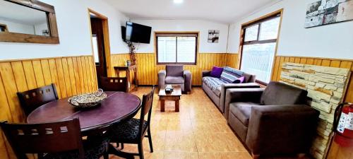 una sala de estar con una mesa y un sofá en Cabaña La Foresta, en Coyhaique