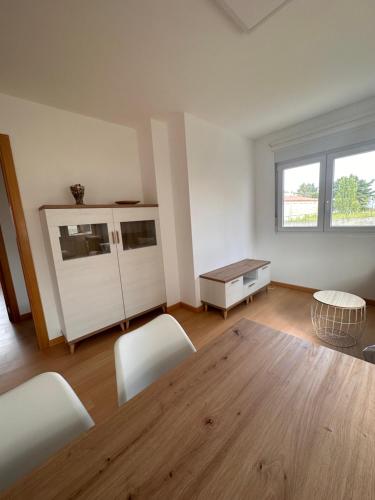 a living room with a wooden table and white chairs at Aserradero - Bajo con terraza y piscina ! in San Martín de Arriba