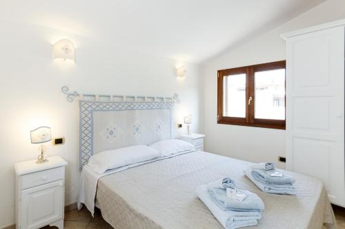 Un dormitorio blanco con una cama con toallas. en Giaco's Apartments 2, en Villasimius