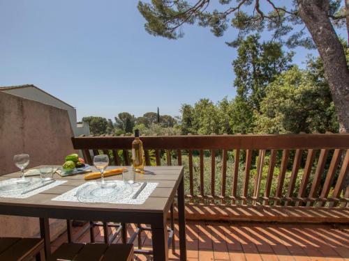 a wooden table with wine glasses on a deck at Studio Le Bali-3 by Interhome in La Ciotat