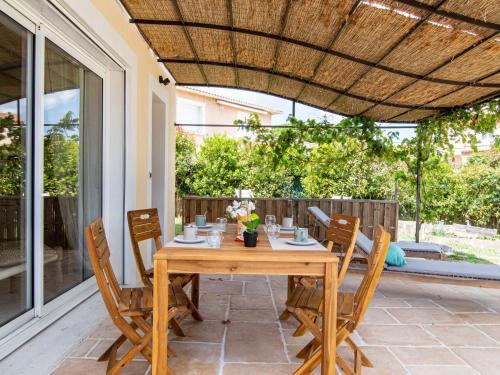 une table et des chaises en bois sur une terrasse dans l'établissement Apartment Le Vallon des Chenes by Interhome, à Saint-Aygulf