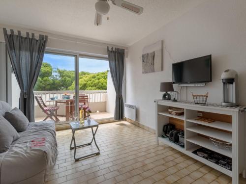 ein Wohnzimmer mit einem Sofa, einem TV und einem Balkon in der Unterkunft Studio La Frégate-13 by Interhome in Le Grau-du-Roi