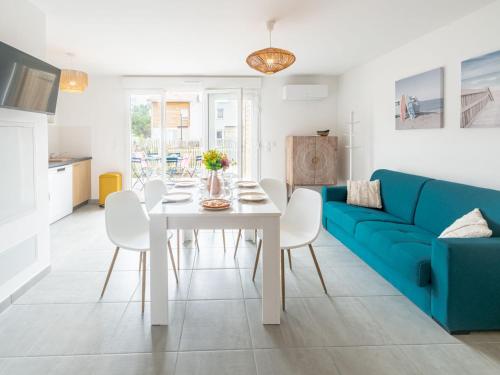 un salon avec un canapé bleu, une table et des chaises dans l'établissement Apartment soleil couchant I03 by Interhome, à Mimizan