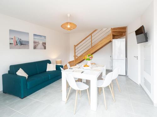 - un salon avec une table blanche et un canapé bleu dans l'établissement Apartment soleil couchant I03 by Interhome, à Mimizan