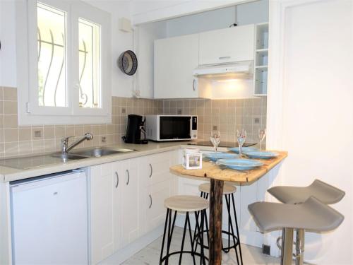 une cuisine avec des placards blancs et un comptoir avec deux tabourets dans l'établissement Apartment Le Mas Kilou by Interhome, à Saint-Aygulf