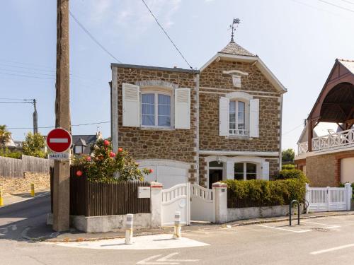 une maison en briques avec une clôture blanche devant elle dans l'établissement Holiday Home L'Eglantine by Interhome, à Saint-Malo