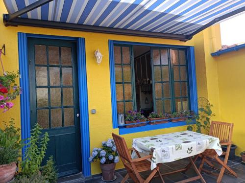 a patio with a table and chairs in front of a yellow house at Villa des Chats in Calais