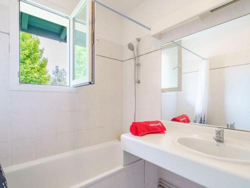 La salle de bains blanche est pourvue d'un lavabo, d'une baignoire et d'une fenêtre. dans l'établissement Apartment Arnaïa by Interhome, à Anglet