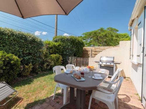 - une table avec des chaises blanches et un parasol dans l'établissement Apartment Les Palatines by Interhome, à Saint-Palais-sur-Mer