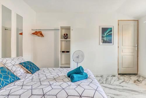 een witte slaapkamer met een groot bed met blauwe kussens bij Appartement climatisé à Béziers avec Jacuzzi & Rétroprojecteur - Le Palais des Glaces in Béziers
