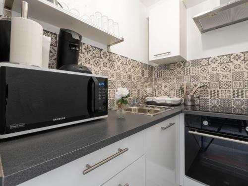 eine Küche mit Mikrowelle und Spüle in der Unterkunft Apartment Los Amigos-14 by Interhome in Le Grau-du-Roi