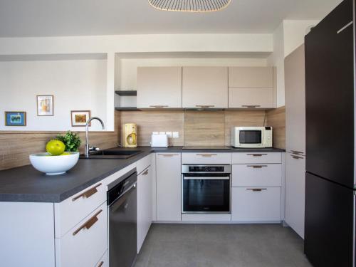 une cuisine avec des armoires blanches et un réfrigérateur noir dans l'établissement Apartment Rive de Cagnes by Interhome, à Cagnes-sur-Mer