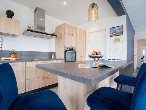 une cuisine avec des placards en bois et un comptoir avec des chaises bleues dans l'établissement Holiday Home Les Agapanthes by Interhome, à Cléder