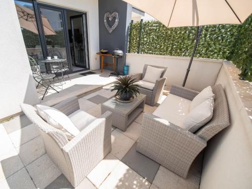 um pátio com cadeiras de vime e um guarda-sol em Apartment Niki by Interhome em Trogir