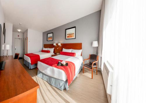 a hotel room with two beds with red sheets at Auberge Royal Versailles in Montréal