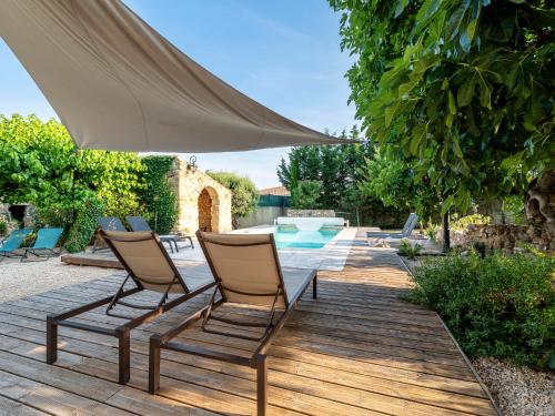 eine Terrasse mit 2 Stühlen und einem Tisch mit einem Sonnenschirm in der Unterkunft Holiday Home Le Mas d'Adélaïs by Interhome in Baron