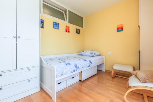una camera con un letto bianco e una sedia di Apartment Yellow Duck - CITY CENTER a Makarska