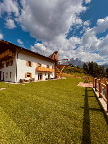 a building with a large grass field in front of it at B&B Maso al Cervo in Fiera di Primiero